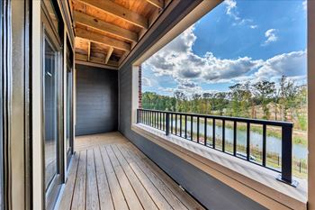 A balcony with a view of a river and trees.